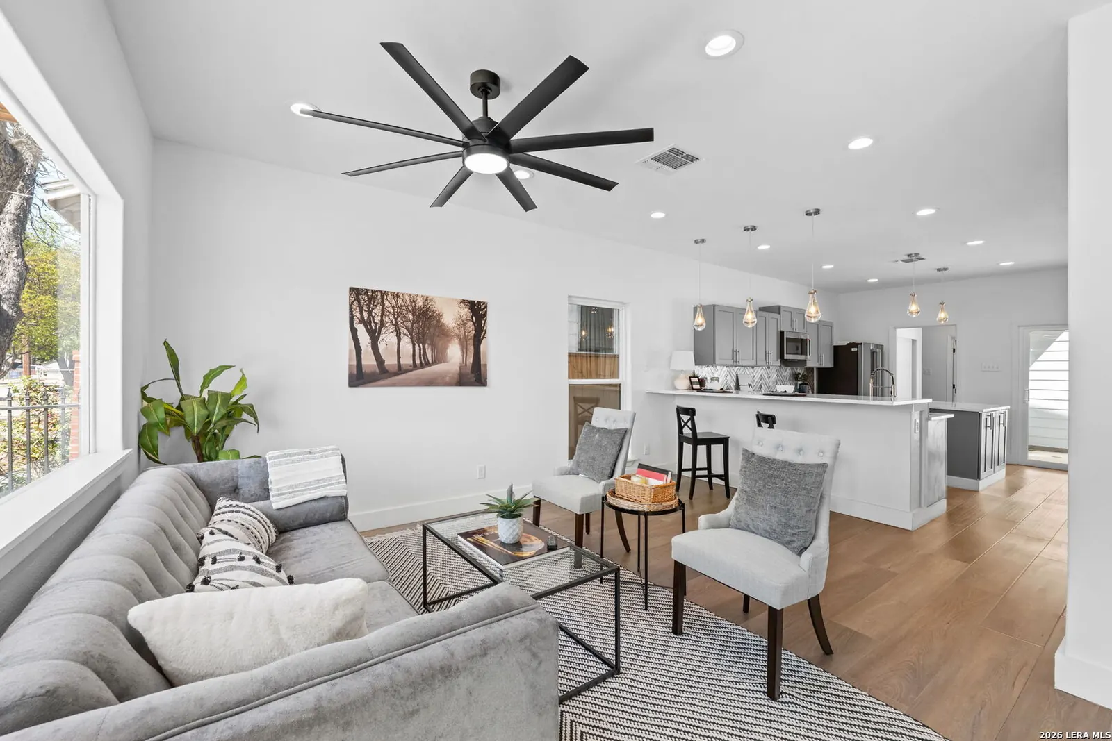 Open kitchen and living space staged with soft seating and greenery